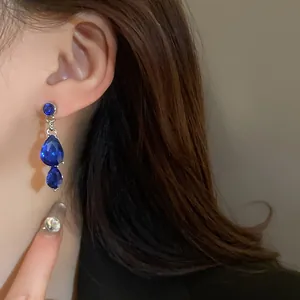 Detail view of vintage style blue water drop rhinestone earrings on model's ear