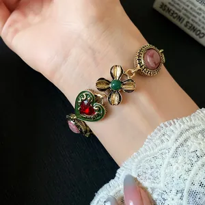 Close-up of vintage gold charm bracelet featuring green heart and flower details