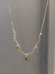 Gros plan d'un collier plaqué or 18 carats avec d'élégants pendentifs gouttes vert et clairs