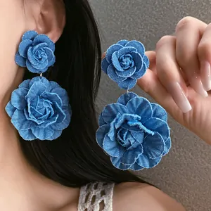 Detailed close-up showing large blue denim fabric flower earrings worn by an Asian model