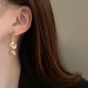 Elegant vintage champagne teardrop earrings with rhinestone detail shown on model's ear