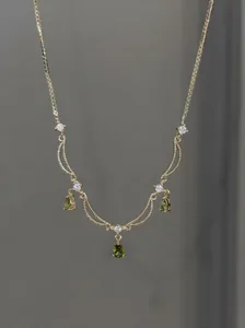 Gros plan détaillé d'un collier plaqué or 18 carats avec pendentifs gouttes verts