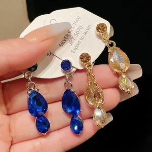 Detailed macro view of elegant vintage water-drop crystal earrings in blue and gold colors