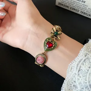 Close-up of vintage heart and flower charm bracelet on female wrist