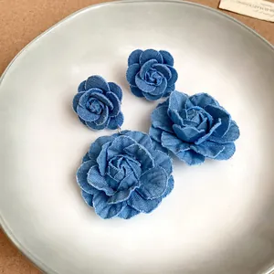 Detail showing the intricate texture of blue denim fabric flower earrings.