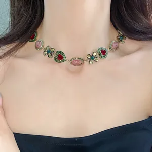 Detailed view of a vintage-style gold choker necklace with heart, flower and cameo motifs.