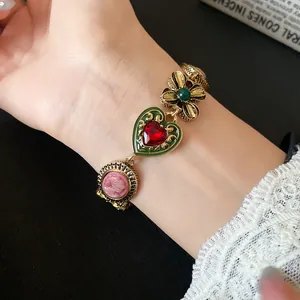 Close-up of a vintage-style gold bracelet with heart and floral charms on a wrist.