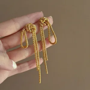Detail shot of gold-plated metal chain knot tassel earrings showing fine texture