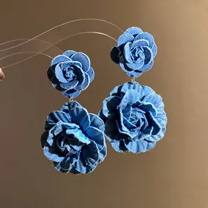 Close-up of blue denim fabric rose drop earrings showing exquisite flower petal texture