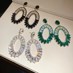 Detailed view of vintage oversized oval drop earrings with emerald and clear crystals