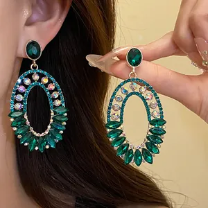 Close-up of vintage oval pendant earrings with green crystals and sparkling rhinestones