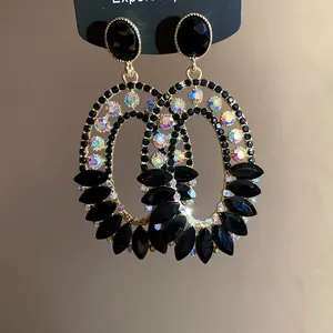 Detailed view of ornate oval dangle earrings with black rhinestones and iridescent crystals.