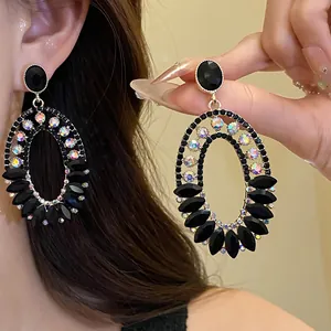 Detailed close-up of vintage oval pendant earrings with black gems and sparkling crystals.