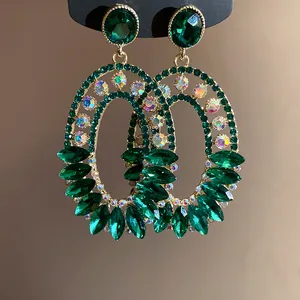 Close-up of emerald green oval dangle earrings with iridescent rhinestones