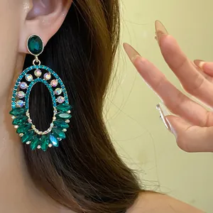 Detailed close-up of vintage emerald green oval drop earrings with sparkling rhinestones