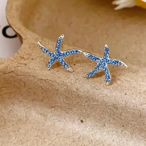 Close-up of starfish stud earrings with vibrant blue rhinestones and 925 silver needles.