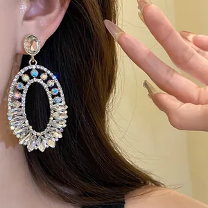 Detailed view of luxury oval rhinestone dangle earrings with AB crystals on model ear