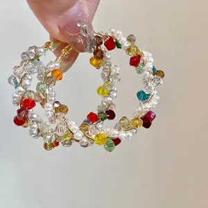 Macro detail of stylish colorful crystal and pearl beaded hoop earrings for women.