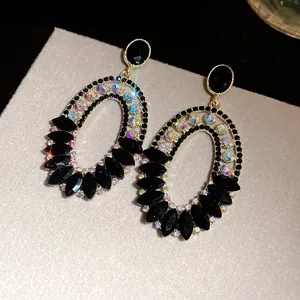 Macro view of luxurious oval drop earrings with black stones and iridescent crystals.