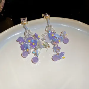 Dettaglio di orecchini a fiore viola con strass scintillanti e aghi in argento.