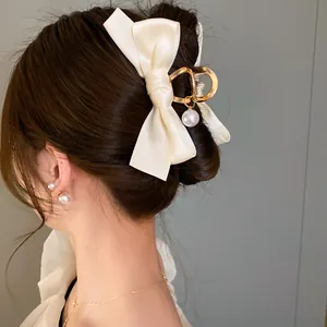 Dettaglio di un elegante fermaglio per capelli con fiocco in raso crema e perla pendente