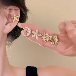 Set of gold metal ear clips with starfish, moon, sun, and flower designs on model