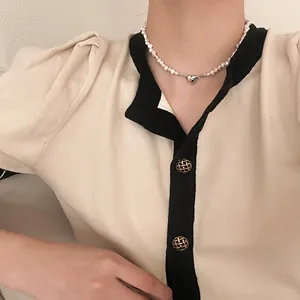 Close-up of a freshwater pearl necklace with a silver heart magnet pendant on a model.