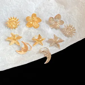 Close-up view of assorted gold and silver metal ear clips in sun, moon, and flower shapes
