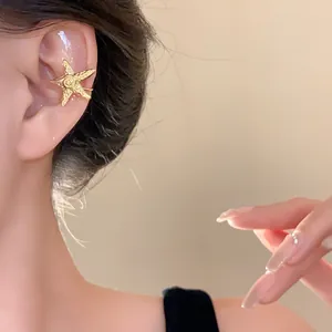 Close-up detail of a textured gold starfish ear cuff worn on an ear, elegant jewelry view.