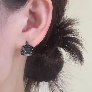 Vintage-style square black stone ear clip earrings with halo setting on model ear