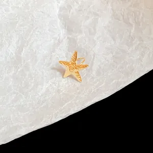 Detail view of a gold-colored metal starfish ear cuff with textured surface design