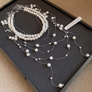 Elegant double-strand pearl necklace with layered tassel chains on a black tray
