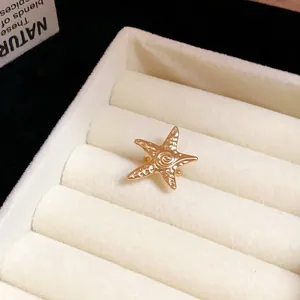 Close-up macro detail of a textured gold starfish ear cuff shown in a jewelry tray