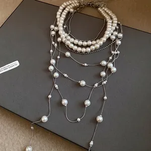 Elegant multi-layered pearl necklace with silver chain tassels on a gray display box