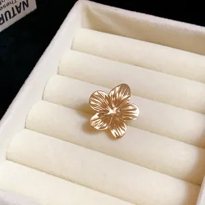 Close-up of golden flower earring detail with textured petals in white jewelry box