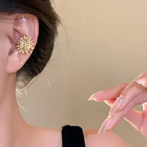 Close-up of gold sun flower ear cuff worn on model's ear, luxury aesthetic