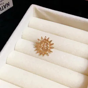 Close-up of a vintage-style gold sun face ear clip earring in a white jewelry display tray