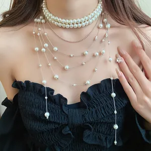 Close-up of elegant double-layer pearl choker with long trailing tassel chains on model