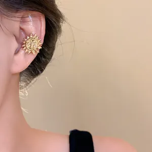 Detailed macro shot of vintage gold sun and moon face ear cuff jewelry on female model