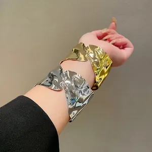 Close-up of gold and silver irregular geometric open cuff bracelets on model's arm