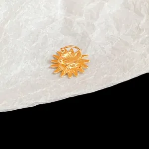 Close-up detail of a golden sun flower non-pierced ear clip on textured white paper
