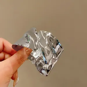 Macro detail of high-shine irregular wavy silver metal cuff bracelet for women
