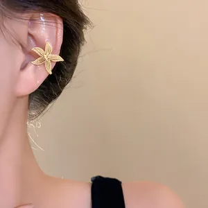 Close-up detail of a textured gold starfish ear cuff elegantly worn on the upper ear.