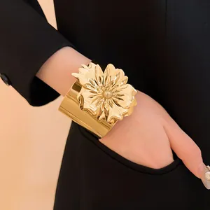 Primer plano de un brazalete de metal dorado con un diseño de flor grande en 3D