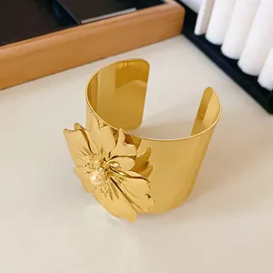 Detalle de un brazalete dorado minimalista con un diseño de flor muy llamativo