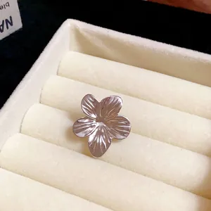 Detailed view of a silver-toned flower ear clip in a cream velvet jewelry organizer.