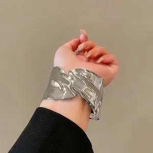 Detailed macro view of an irregular silver metal cuff bracelet worn on a woman's wrist