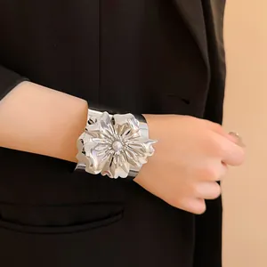 Vista detallada de un gran brazalete de flores plateado con una perla en el centro