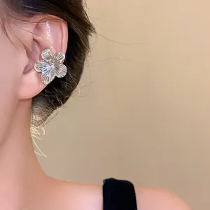 Elegant silver metallic flower ear cuff shown on model's ear for detailed texture