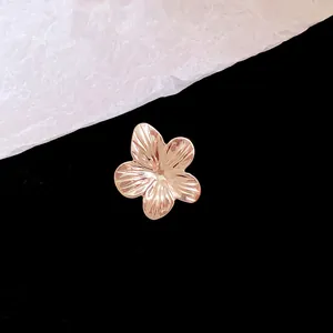 Macro view of metallic flower ear clip with fine textured petals in rose gold finish